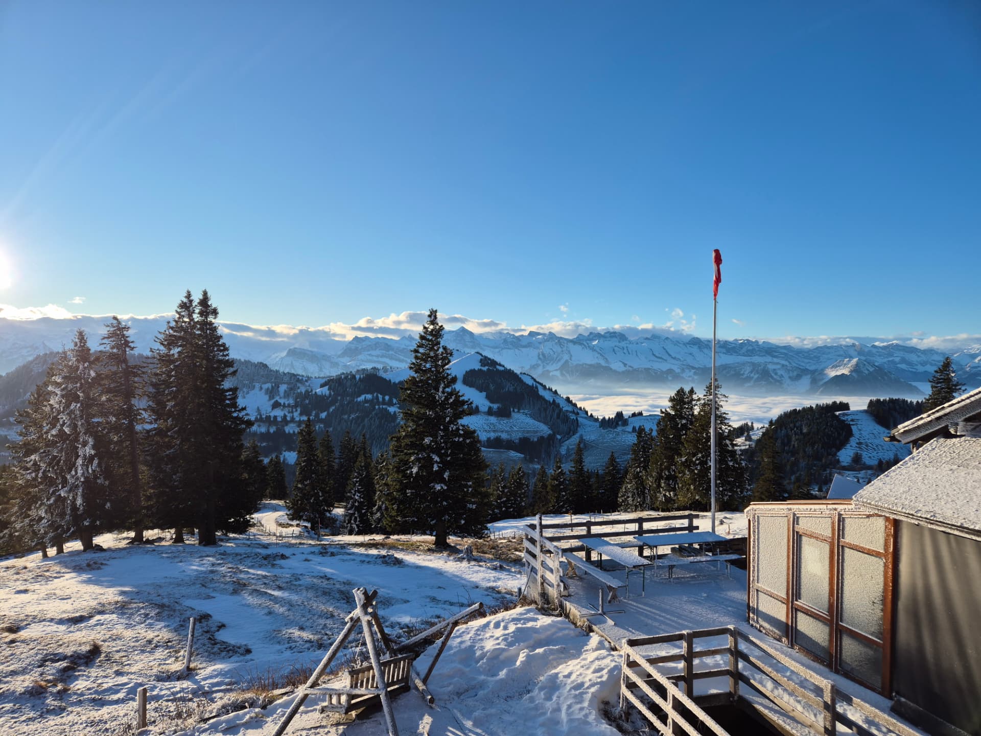 Verschneite Berghütte in den Schweizer Bergen bei Sonnenaufgang, dahinter das Alpenpanorama – Ort des Männer-Retreats